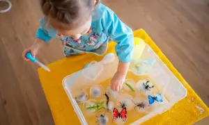 Niña haciendo experimentos para niños, liberando insectos de hielo con un gotero.