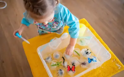 Niña haciendo experimentos para niños, liberando insectos de hielo con un gotero.