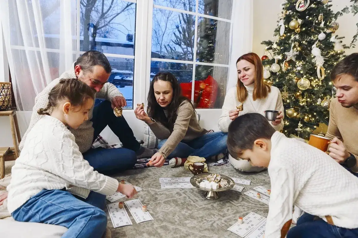 Familia reunida jugando juegos interactivos de navidad junto al árbol.