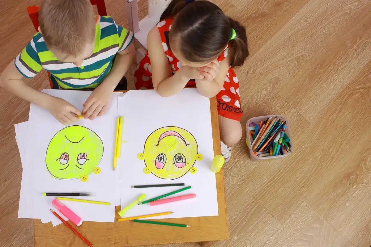 Ni&ntilde;os dibujando caras sonrientes y tristes en una actividad para trabajar la empat&iacute;a.